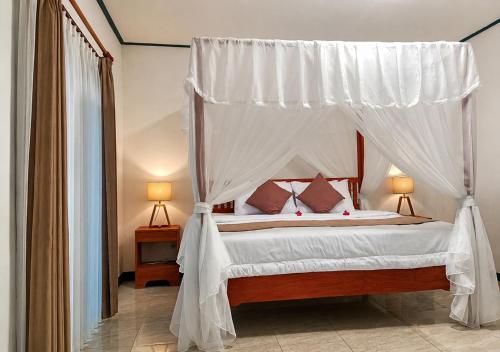a bedroom with a canopy bed with two lamps at Lonthar B&B - Adults Only in Riung