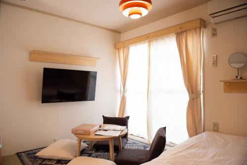 a bedroom with a bed and a table and a tv at Guesthouse Life Field in Kurashiki