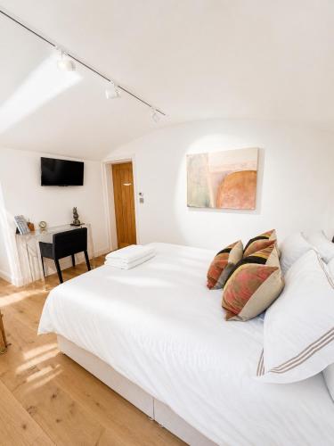 a white bedroom with a bed and a desk at The Old Pub Wiltshire A Unique Luxury Cellar Retreat with Private Sauna Gym and Movie Room in Patney