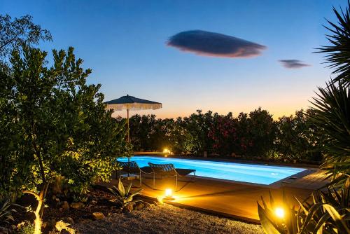 a swimming pool with lights in a backyard at night at Villa Polyxeni Lavender 150m from the sea in Politika