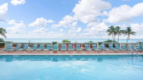 a swimming pool with chairs and the ocean in the background at Hollywood Beach Tower - Studio Suite in Hollywood