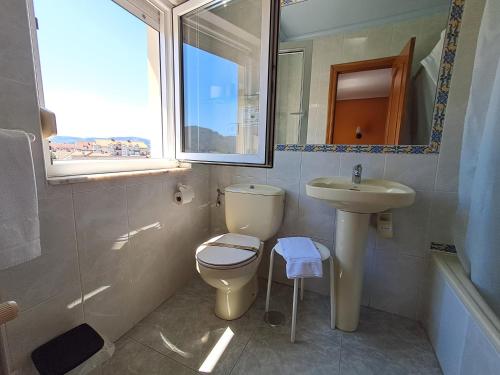 a bathroom with a toilet and a sink and a mirror at Hostería La Casona in Noja