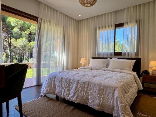 a bedroom with a large bed and a large window at Le Forestier in Dar el Hajri