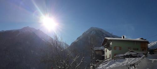 a house on a snowy mountain with the sun in the sky at Ferienhaus Nadine in Kappl