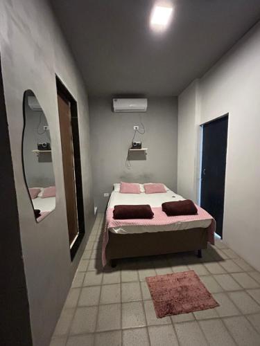 a bedroom with a bed with pink sheets and a mirror at Suíte Sete Colinas in Garanhuns