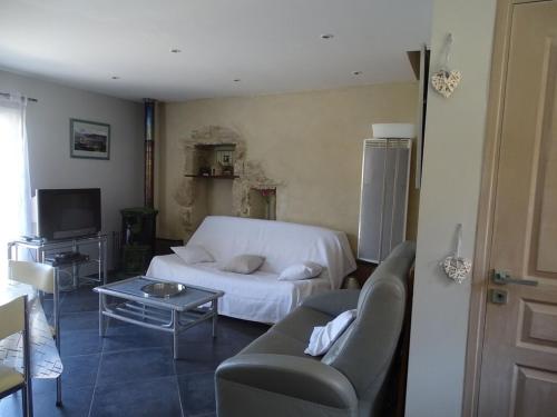 a living room with a white couch and a table at Oustalou in Saint-Rome-de-Tarn