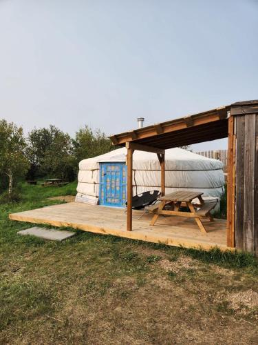 a large yurt with a picnic table and a wooden deck at COTC - The Coulee Yurt - Suite in Castor