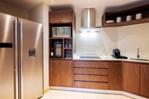 a kitchen with wooden cabinets and a stainless steel refrigerator at Royalton Grenada, An Autograph Collection All-Inclusive Resort in Bamboo