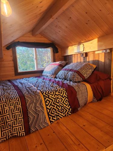 two beds in a room in a log cabin at COTC - The Grouse House - Suite in Castor