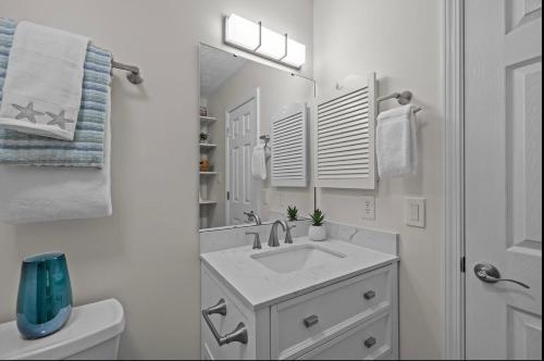 a bathroom with a sink and a mirror and a toilet at Mystic Sands in Emerald Isle