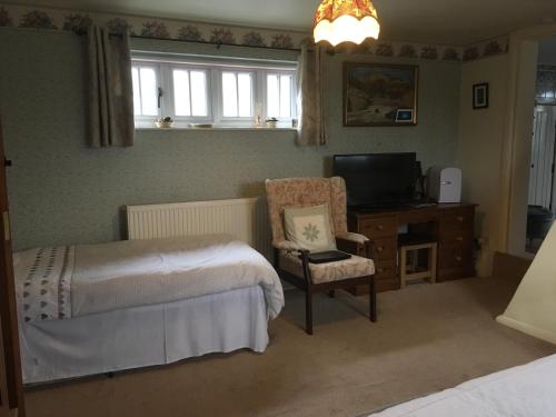 a bedroom with a bed and a chair and a television at Hungarton Bed & Breakfast in Hungerton