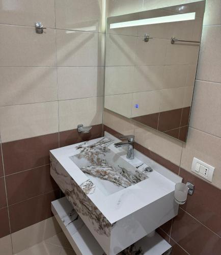 a bathroom with a marble sink and a mirror at Rana e Hedhun Beach House in Shëngjin