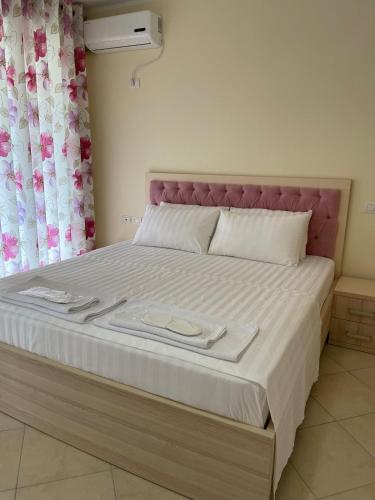 a bedroom with a large bed with a pink headboard at Rana e Hedhun Beach House in Shëngjin