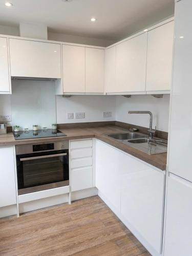 a white kitchen with white cabinets and a sink at Blanco Brillo in Colchester