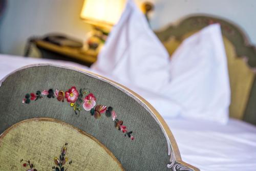 a chair with flowers on top of a bed at Hotel Brunella in San Vigilio Di Marebbe