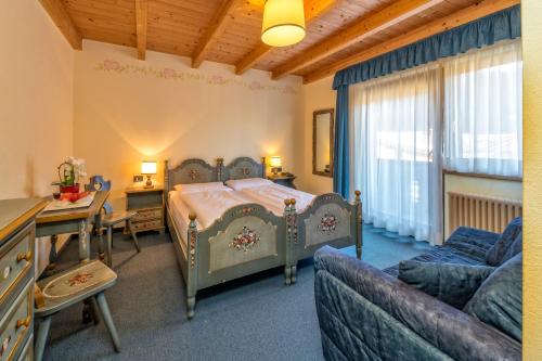 a bedroom with a bed and a couch and a table at Hotel Brunella in San Vigilio Di Marebbe