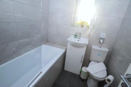 a bathroom with a tub and a toilet and a sink at Glenroy House Swansea in Swansea