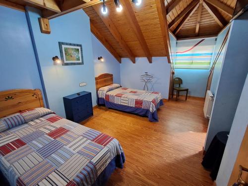 a bedroom with two beds and a wooden floor at Hostería La Casona in Noja