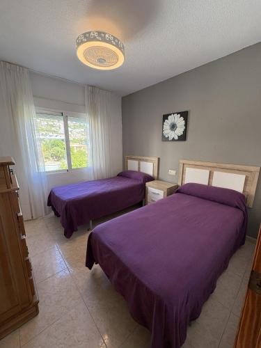 two beds in a room with purple sheets at Alpen1 Finca Simo in Peniscola