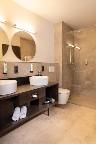 a bathroom with two sinks and a shower at Altstadthotel Arch in Regensburg