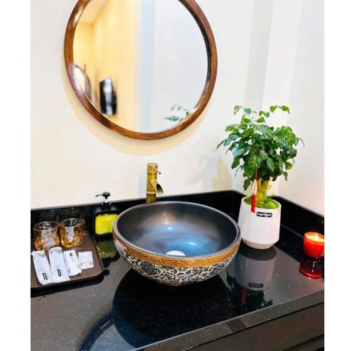 a sink with a bowl on a counter with a mirror at HueS Home in Hue