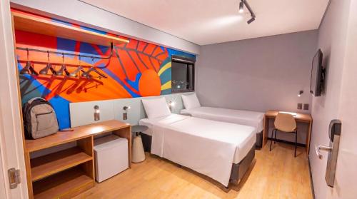 a bedroom with a bed and a desk and a painting at IBIS STYLES PETROLINA in Petrolina
