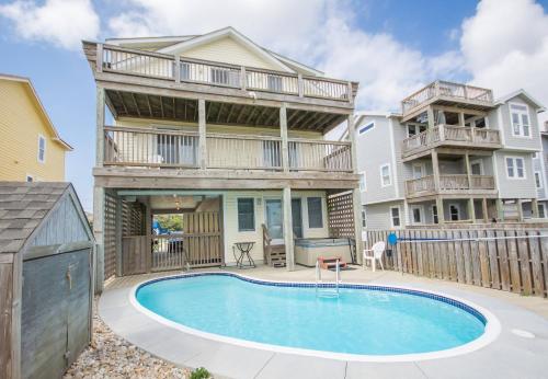 a house with a swimming pool in front of a house at Carolina Kai II - Kitty Hawk MP 3, 228 Yards to Beach, Ocean View, Pool, Hot Tub in Kitty Hawk