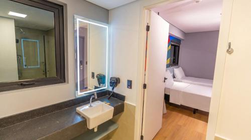 a bathroom with a sink and a mirror and a bed at IBIS STYLES PETROLINA in Petrolina