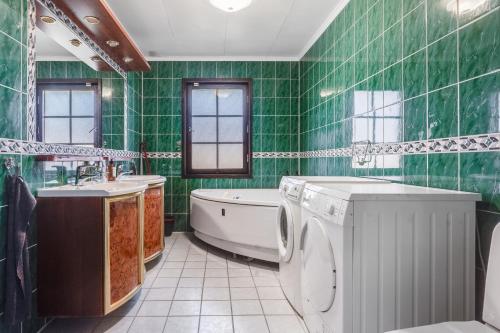 a green tiled bathroom with a tub and a washing machine at Gula villan in Påarp
