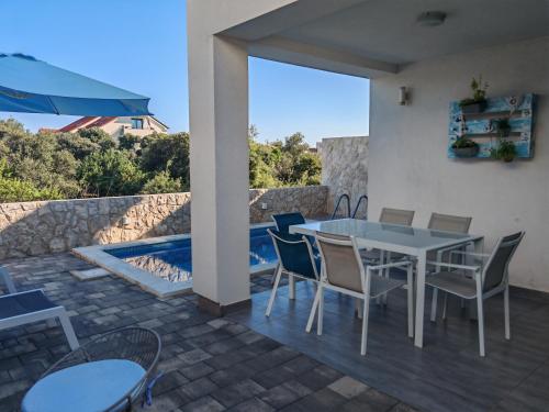 a patio with a table and chairs and a swimming pool at PALMandre (Pag Apartment Luxurious) in Mandre