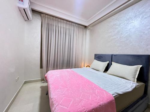 a bedroom with a pink bed and a window at Appartement Climatisé 2 Chambres à Marrakech Proche Golf & Jamaâ El Fna in Marrakesh