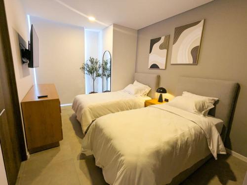 a hotel room with two beds and a television at Increible departamento en Punto Sur in Los Gavilanes