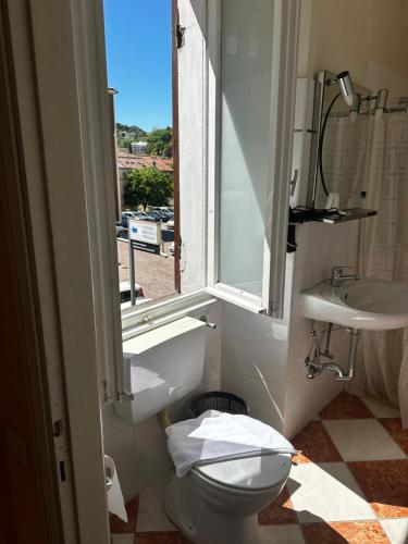 a bathroom with a toilet and a sink and a window at Hotel Spagna in Arona
