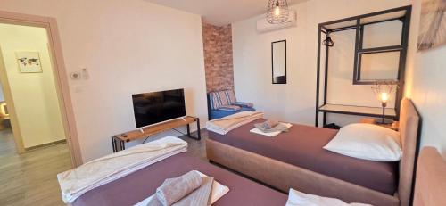 a hotel room with two beds and a tv at Villa Kajgo-Pag in Pag