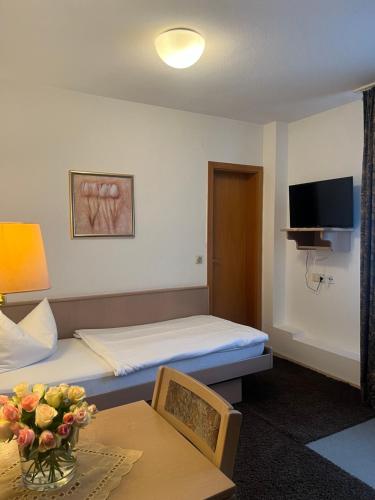 a room with a bed and a table with a vase of flowers at Zum Flößer in Neckartenzlingen