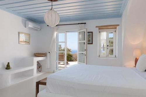 a white bedroom with a bed and a window at Cozy Villa in Mykonos