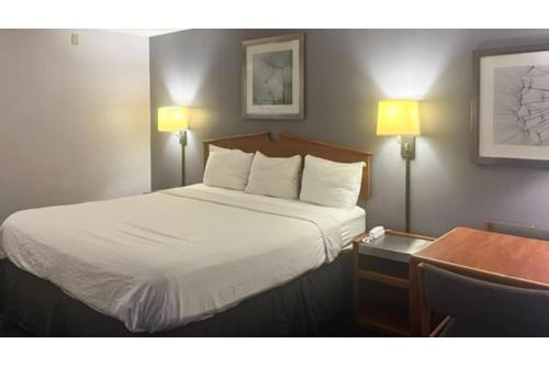a bedroom with a bed with white sheets and a desk at Studio 6 Suites Louisville KY Airport/Expo Center in Louisville