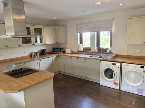 a kitchen with white cabinets and a washer and dryer at Abernethys Cottage in Connel