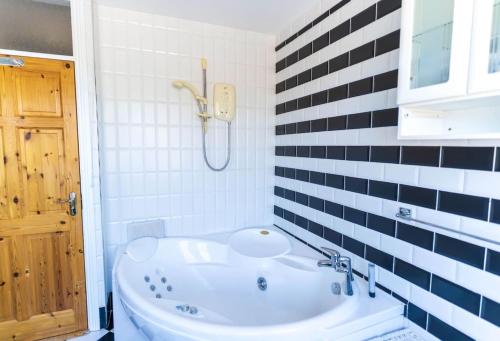 a bathroom with a tub and a phone on the wall at The Townhouse in Cahersiveen
