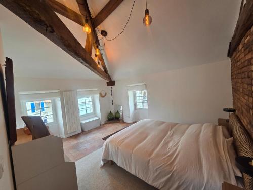 a bedroom with a white bed and some windows at Les terrasses de la moine in Cholet