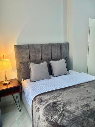 a bedroom with a bed with a headboard and a table at Black-Oak Apartments in Lusaka