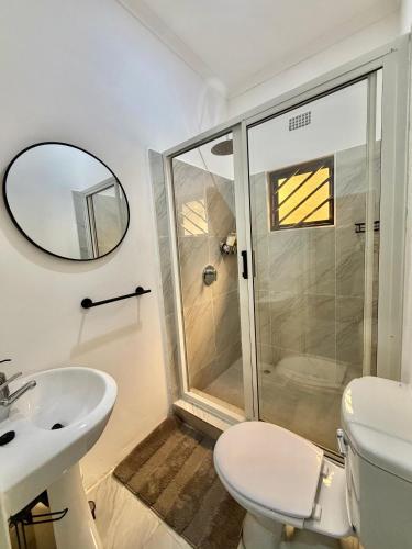 a bathroom with a shower and a toilet and a sink at Black-Oak Apartments in Lusaka