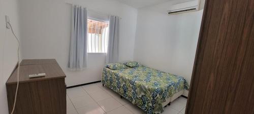 a bedroom with a bed and a desk and a window at Casa de praia em Guriri in Guriri