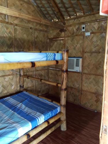 two bunk beds in a room with a fan at Balai-Cintai Beach Resort in Castañas
