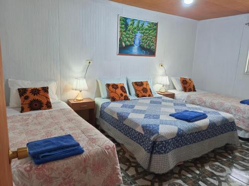 a room with two beds and two lamps on tables at cabañas Te Pito Kura in Hanga Roa