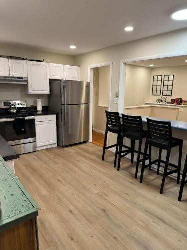 a kitchen with black chairs and a stainless steel refrigerator at Fun 5 Bedroom Lakefront Cottage in Bethel