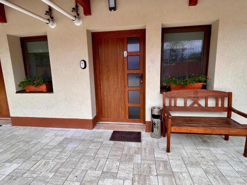 a wooden bench sitting outside of a house with a door at BT Apartman in Miercurea-Ciuc