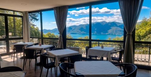 ein Restaurant mit Tischen und Stühlen und Blick auf einen See in der Unterkunft Hotel Montegrino Lakeview in Montegrino Valtravaglia