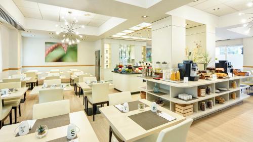 a restaurant with white tables and chairs and a counter at Sercotel Alcalá 611 in Madrid