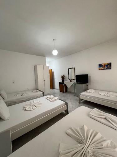 a room with three beds and a mirror at City Center Hotel in Sarandë